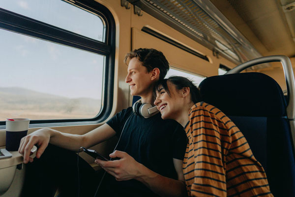 Junges Paar sitzt lachend im Zug