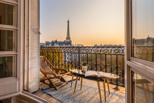 Sicht aus auf einen Balkon mit Tisch und Stühlen auf den Eiffelturm in Paris
