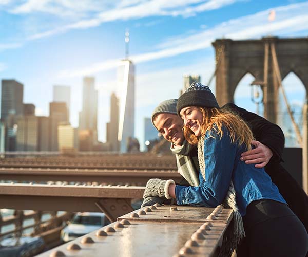 Reisende auf der Brooklyn Bridge mit Skyline von New York City im Hintergrund