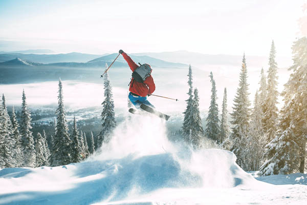Skifahrer springt in die Lust auf einer schneebedeckten Piste