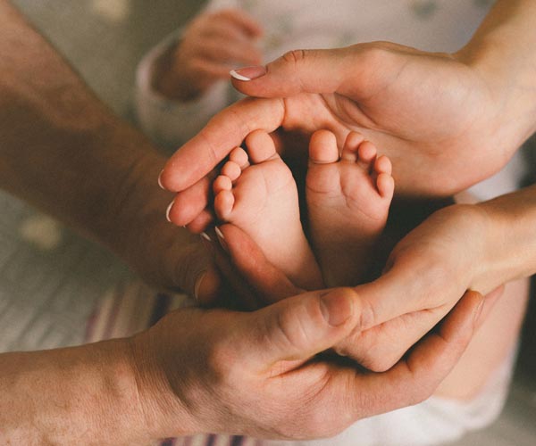 Hände von Eltern, die Babyfüsse halten
