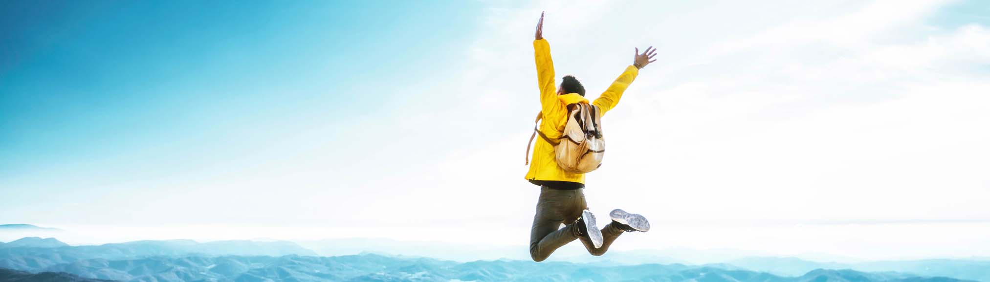 Mann springt in die Luft vor Freude, abgesichert durch die Reisestornoversicherung und geschützt vor hohen Kosten