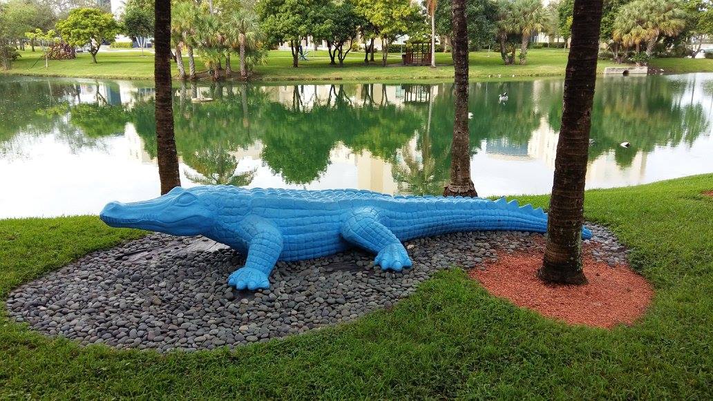 Ein blauer Alligator aus Plastik an einem Ufer
