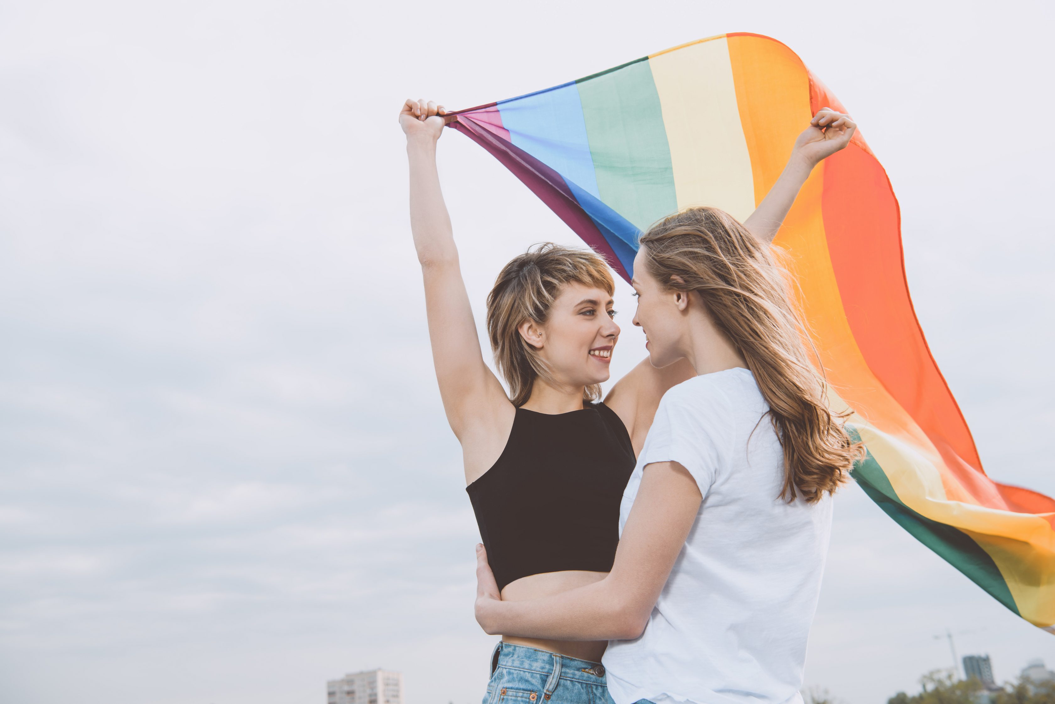 Zwei Frauen unter einer LGBTQ+ Flagge
