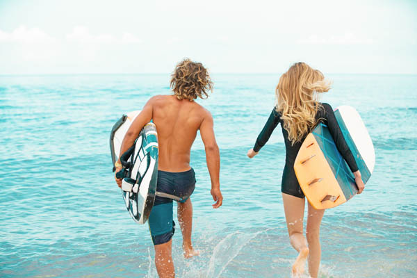 Mann und Frau mit Surfboards gehen ins Meer