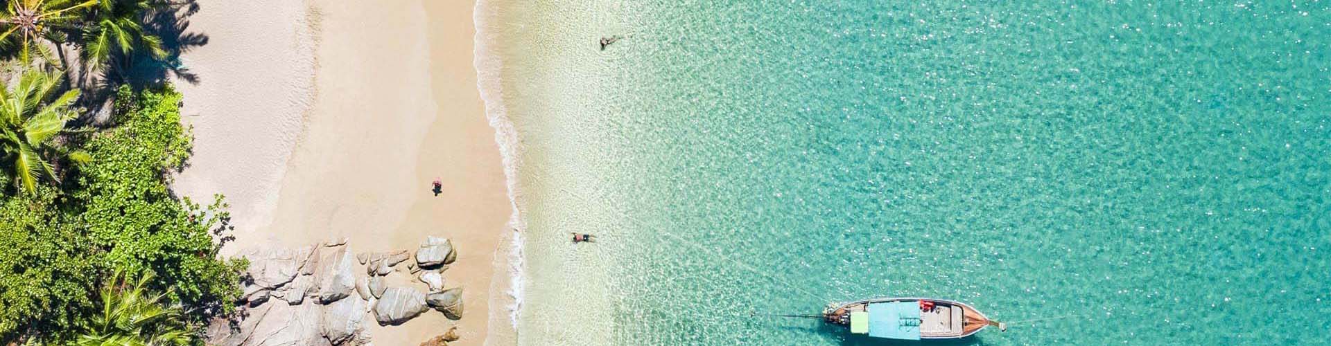 Sandstrand mit Palmen, Meer und Boot