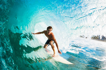 Surfer der auf einem Surfbrett durch eine Welle surft
