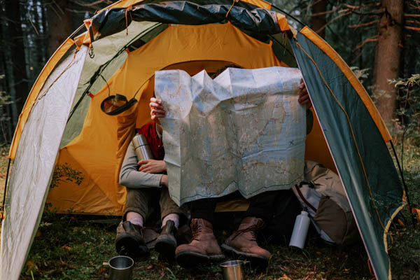 Zwei Personen im gelben Zelt, schauen sich eine Karte an
