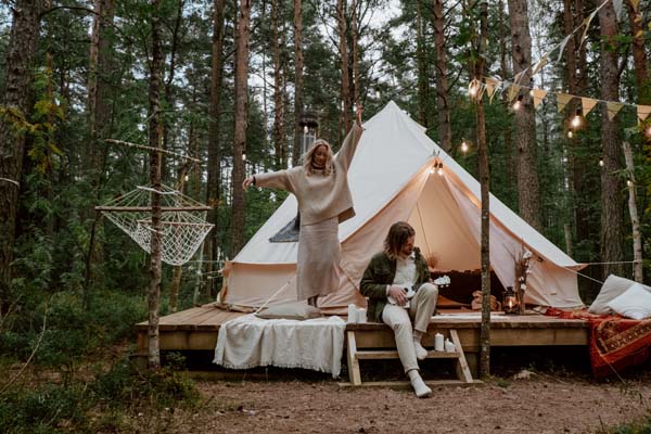 Ein Paar campt im Wald, weißes Luxus-Zelt