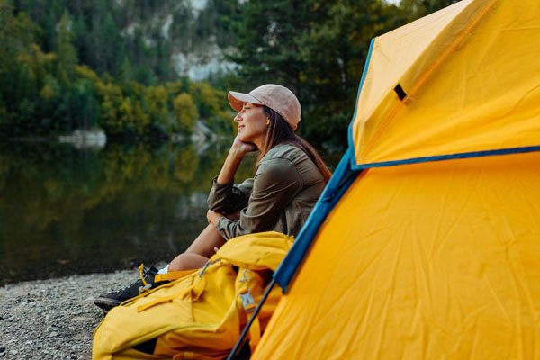 Frau macht Urlaub in der Natur, mit gelbem Zelt