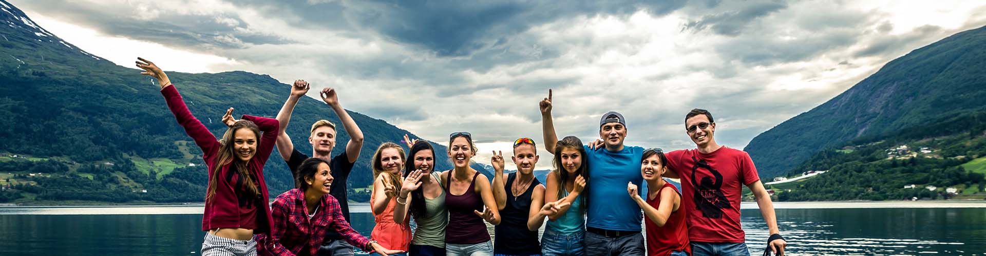 Gruppe von jungen Menschen in Urlaub, Gruppenreise, im Hintergrund Berge und See
