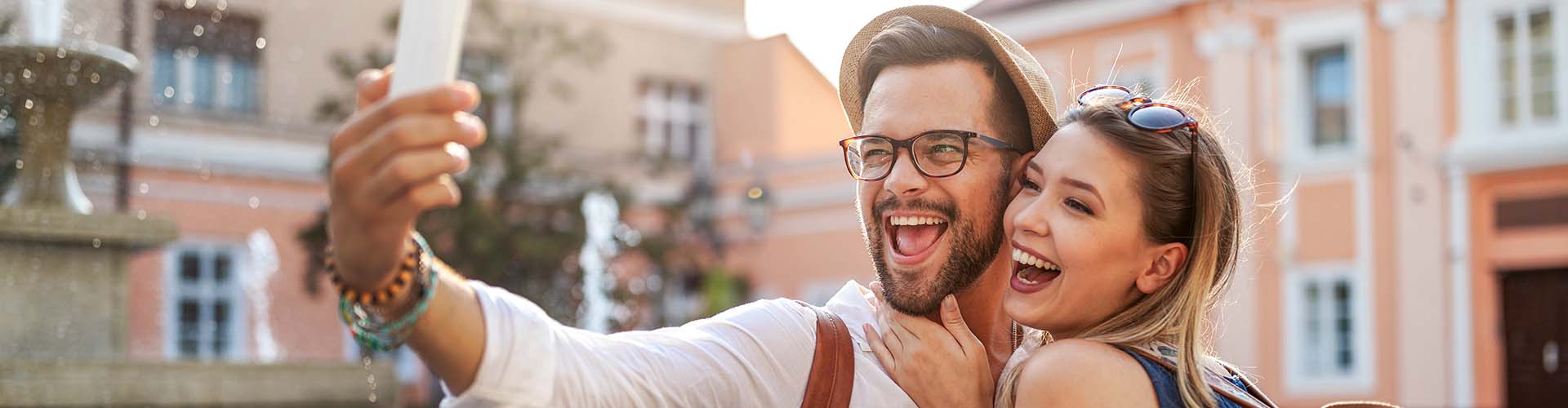 Glückliches Pärchen auf Urlaub, macht Selfies mit einem Mobiltelefon