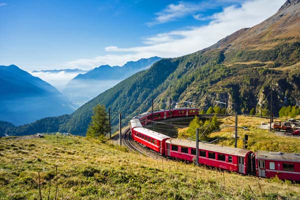 Roter Zug fährt durch eine malerische Berglandschaft