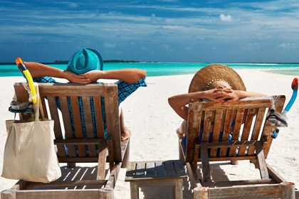 Mann und Frau entspannen in Liegesesseln am Strand, Ausblick aufs Meer