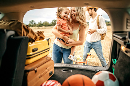 Familie mit Kleinkind reist mit Koffern in einem Auto