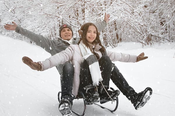 Schneebedeckte Landschaft, Mann und Frau sitzen auf einem Schlitten