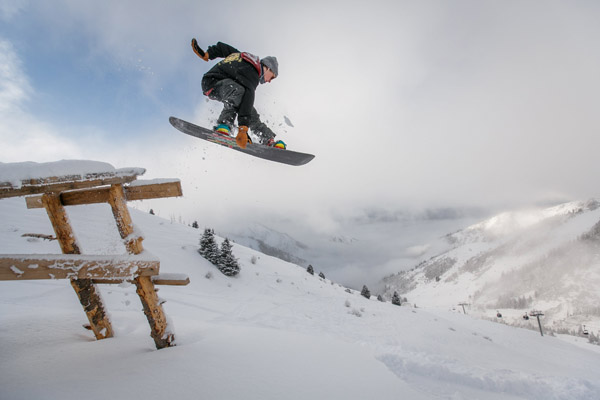 Schneebedeckte Piste, Snowboarder springt