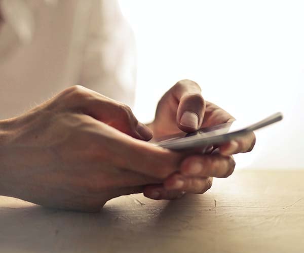 Person nutzt Smartphone, um Informationen zu Reiseversicherung und Serviceleistungen abzurufen