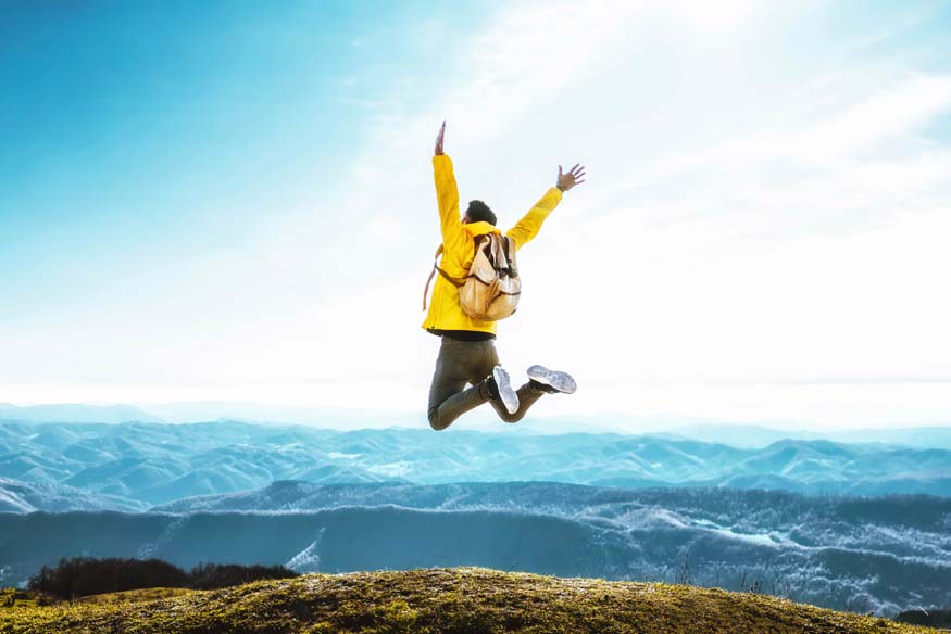 Mann springt in die Luft vor Freude, gut versichert mit einer Reisestornoversicherung