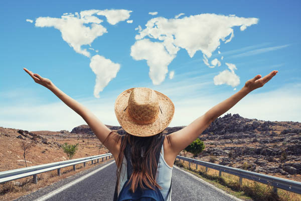 Junge Frau mit Hut, über ihr eine Weltkarte aus Wolken, die sie zu umarmen scheint