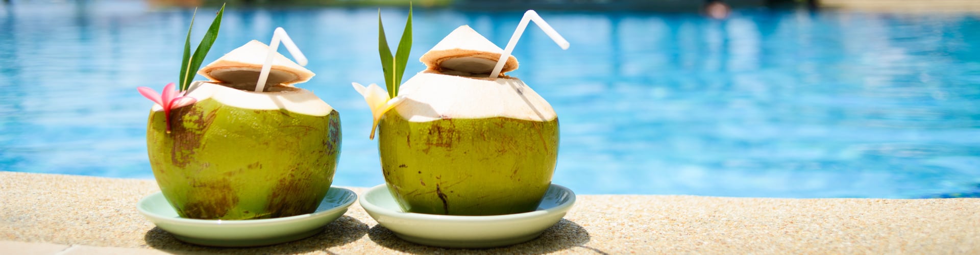 Zwei Kokosnüsse mit Getränk und Strohalm am Pool